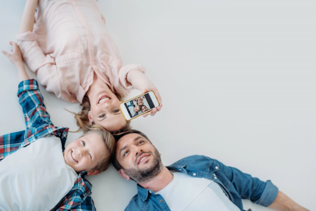 Eltern mit Kind liegen auf dem Boden und machen ein Selfie. wir finden einen Weg unserm Kind die Trennung zu erklären!